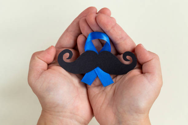 istock Mustache pattern with blue ribbon symbol in child's hands. November movember concept. 1044456740