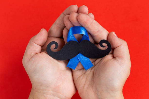 istock Mustache pattern with blue ribbon symbol in child's hands. November movember concept. 1044456744