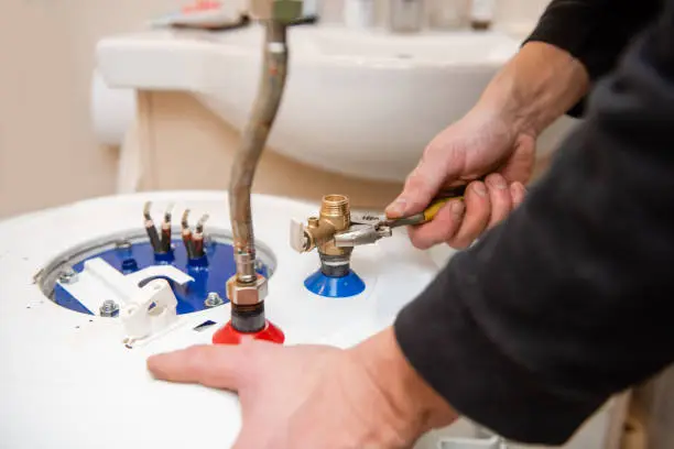 Home bathroom water heater fixing by hands close up