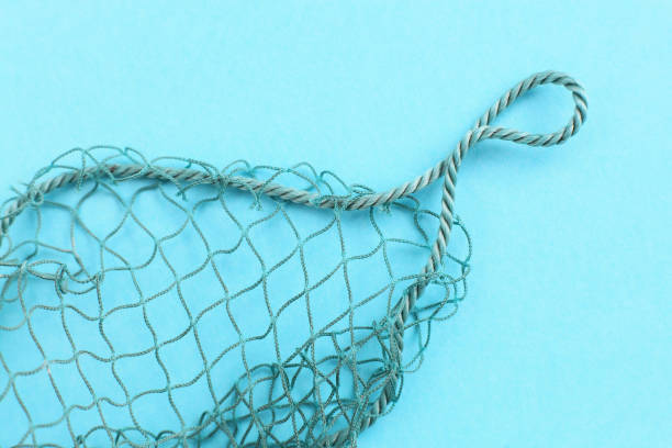 Fishing net with space for your text. Blue background for a fishery theme. Fishing net with space for your text. Blue background for a fishery theme. fishing net photos stock pictures, royalty-free photos & images