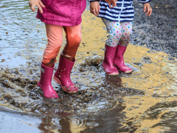 istock Playful child outdoor jump into puddle in boot after rain 1044460934