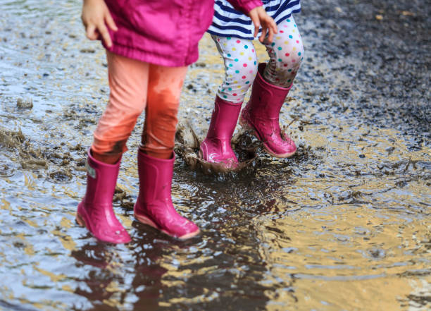 istock Playful child outdoor jump into puddle in boot after rain 1044460966