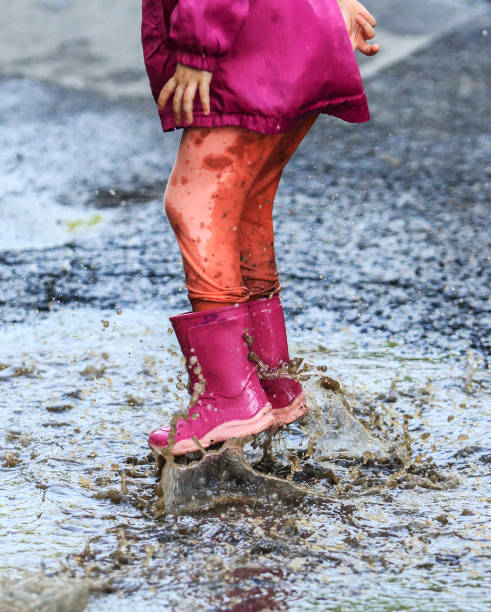 istock Child outdoor jump into puddle in boot after rain 1044460976
