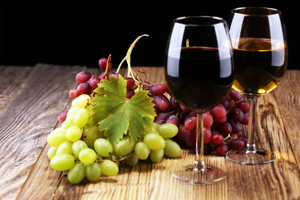 istock White wine and red wine in a glass with fall grapes on rustic background. 1044492738