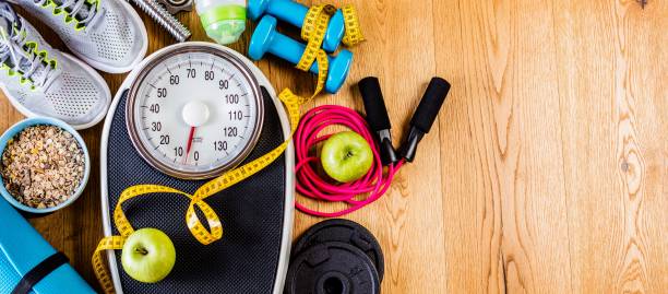 equipo de deportes y entrenamiento sobre un suelo de madera con snacks saludables, pérdida de peso y concepto de actividad física - weight scale apple comparison balance fotografías e imágenes de stock