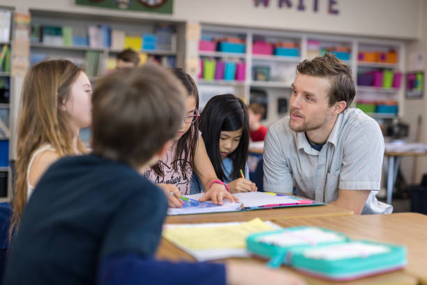 istock Male teacher helping several of his 4th grade students 1044495576