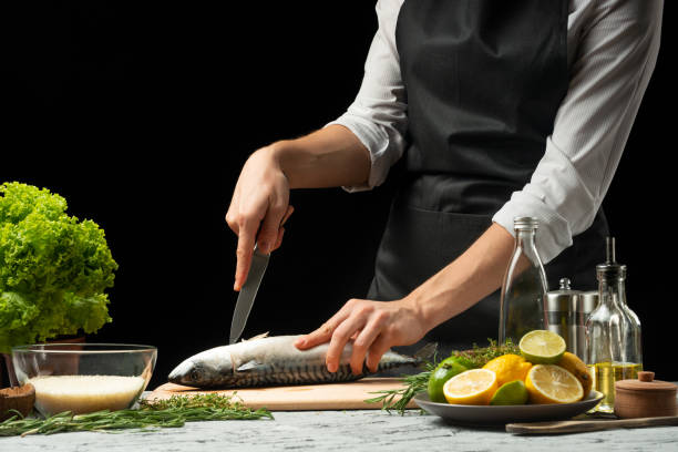 istock Slicing fish by the chef on a black background 1044506350