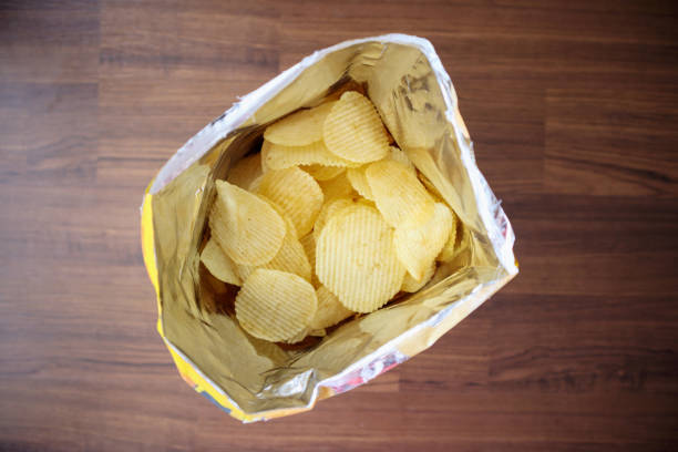 istock Potato chips in open snack bag close up on table floor 1044528058
