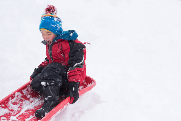 istock Children happy and playful while joyfully sledding during a big snow storm 1044528142