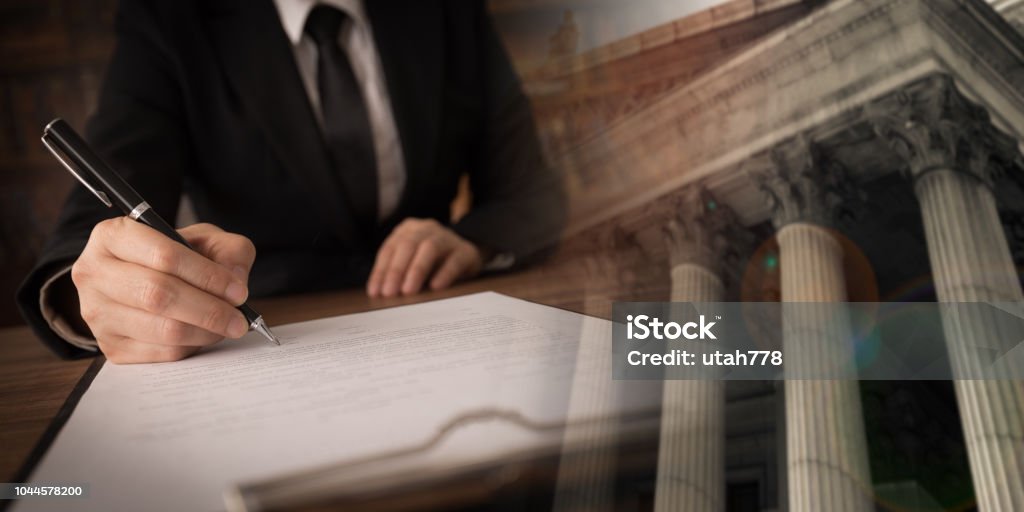 lawyer attorney working lawyer or attorney signing legal document and agreement with court background. legislation law legal concept Government Stock Photo
