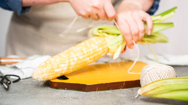 istock Shucking organic corn to make Mexican corn on the cob Elote. 1044605742