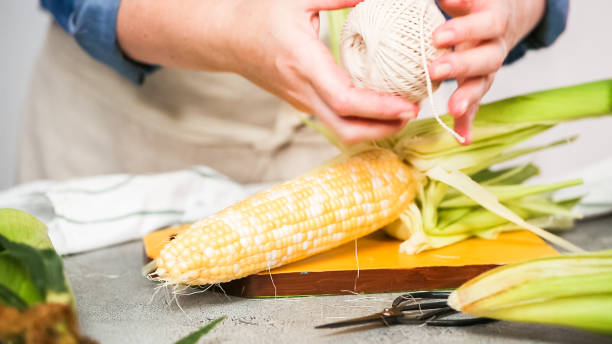 istock Shucking organic corn to make Mexican corn on the cob Elote. 1044607842