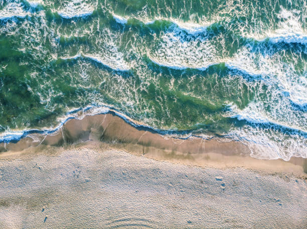 vista aérea das ondas do mar batendo na praia. - south wales - fotografias e filmes do acervo