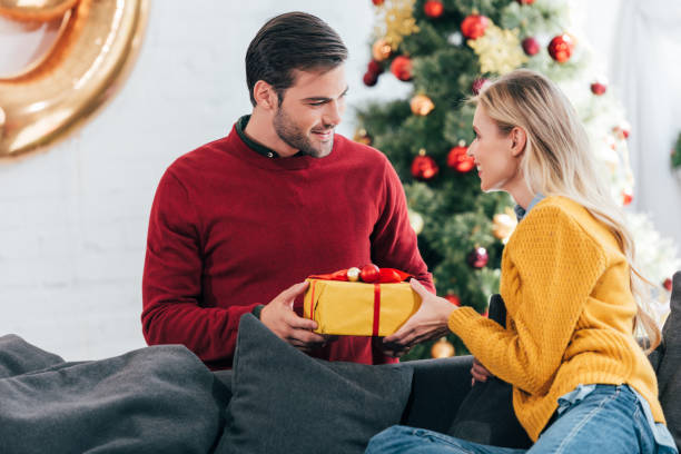istock happy couple gifting present at home with christmas tree 1044645872