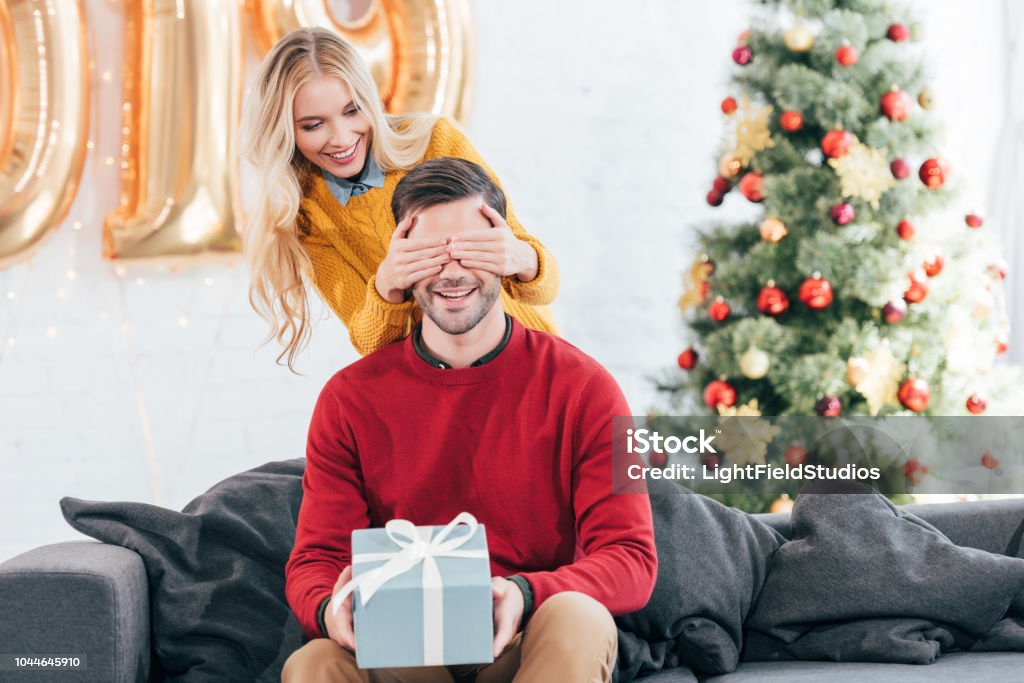 Foto de Garota Fechar Os Olhos E Fazer Surpresa Com Caixa De Presente Para  O Namorado Em Casa Com A Árvore De Natal e mais fotos de stock de 2019 -  iStock