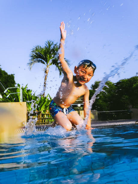 istock boy playing water in swimming pool 1044663720