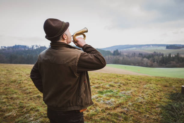 man hunter plays a bugle at the end of the hunt. - trumpet musical instrument wind instrument flugelhorn imagens e fotografias de stock