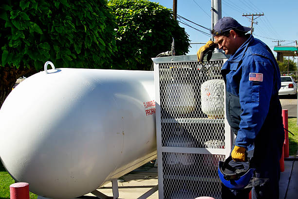 Large gas tank, with profile of a manual laborer leaning against cage full of smaller propane canisters