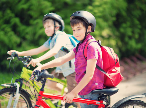 istock Children with rucksacks riding on bikes in the park near school 1044675430
