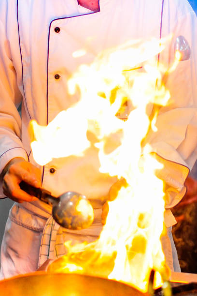 Flame cooking, Fire burn is cooking on iron pan, Chef in restaurant kitchen at stove with pan