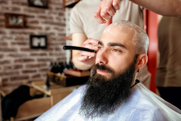 istock Professional master hairdresser shaves client head 1044686064