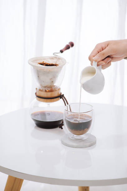 istock Man pouring milk into glass with cold brew coffee on table 1044692468