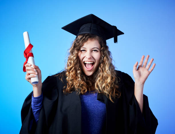 istock Beautiful young graduate waves, holding her diploma and laughing 1044696142