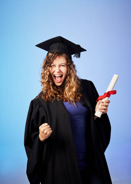 triumphant young female graduate punching air and smiling - grad portrait imagens e fotografias de stock