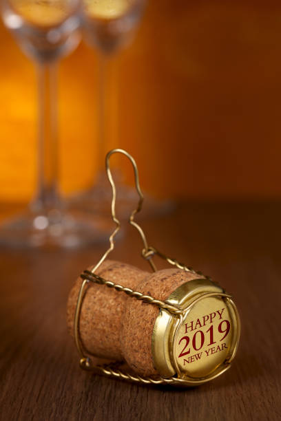 istock Champagne cork, 2019 on cap, two glasses on wooden background. 1044697050
