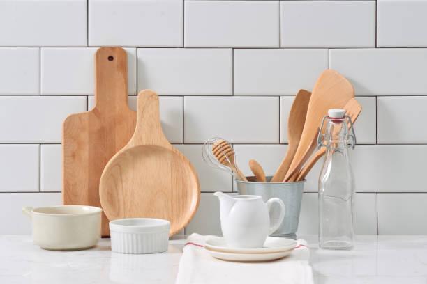 istock Simple rustic kitchenware against white wooden wall: rough ceramic pot with wooden cooking utensil set, stacks of ceramic bowls, jug and wooden trays. 1044707886