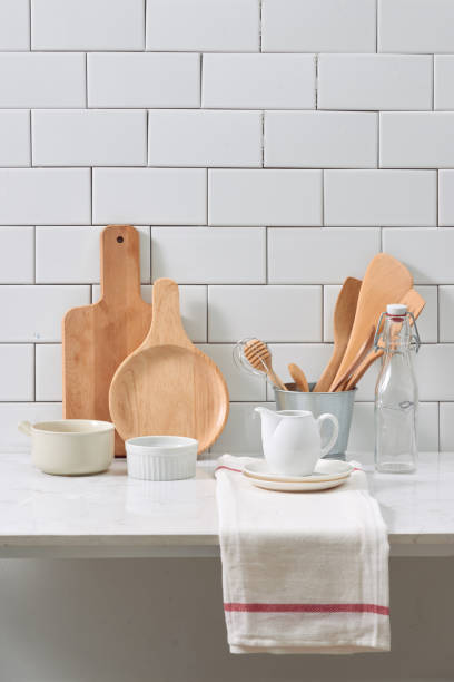 istock Simple rustic kitchenware against white wooden wall: rough ceramic pot with wooden cooking utensil set, stacks of ceramic bowls, jug and wooden trays. 1044708792