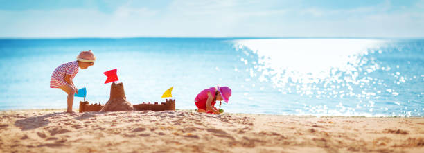 jungen und mädchen spielen auf den strand - sandburg struktur stock-fotos und bilder