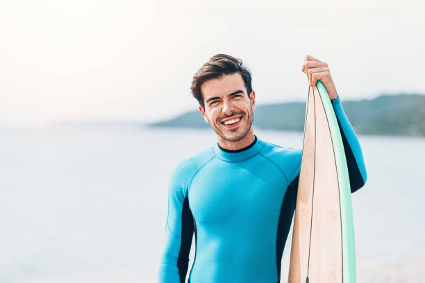 istock Cheerful surfer holding his board on the beach 1044712458
