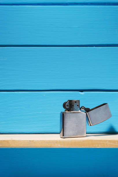 istock Gasoline lighter, metal lighter on a blue wooden table background 1044725776