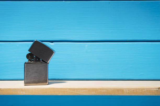 istock Gasoline lighter, metal lighter on a blue wooden table background 1044726336