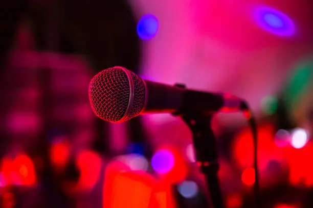 Photo of Microphone stands on stage in a nightclub. Bright club light shines on MIC. Performances in the night club