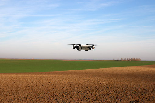 The drone is flying over the plowed field agriculture