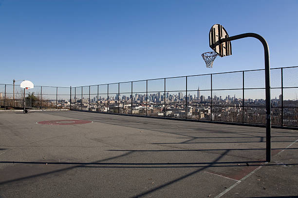 Illuminated basketball playground with red pavement, modern new basketball net and lens flares on background.