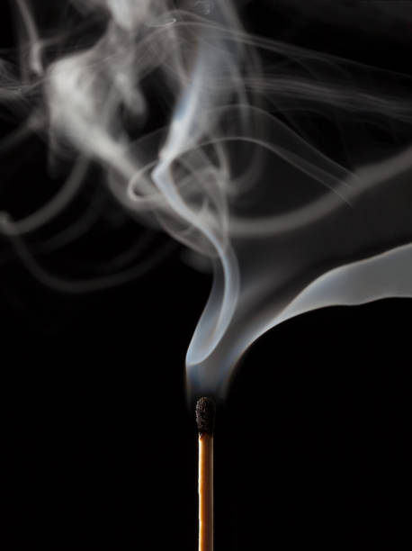 Smoking matchstick, just extinguished, on dark background stock photo