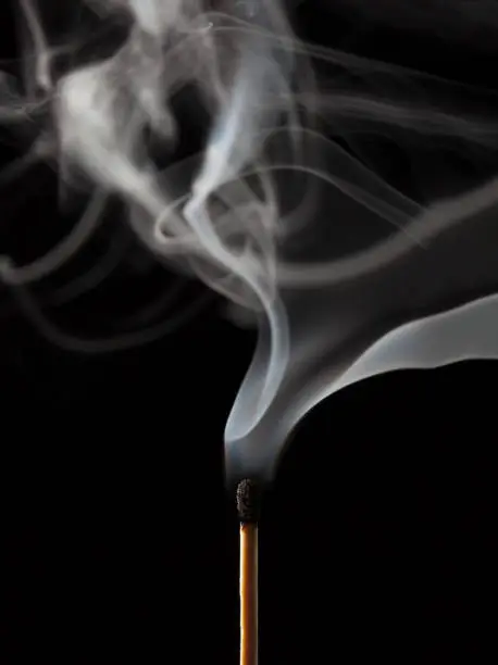Photo of Smoking matchstick, just extinguished, on dark background