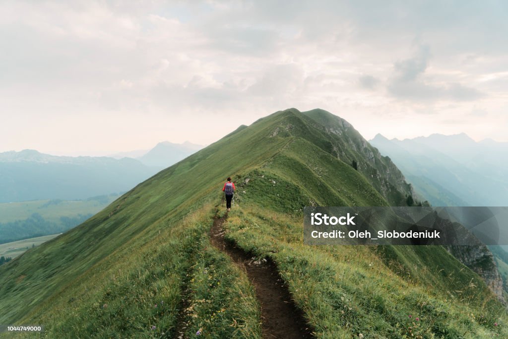 Woman hiking on the mountain ridge in Swiss Alps Young Caucasian woman in hiking on the mountain ridge in Swiss Alps Success Stock Photo