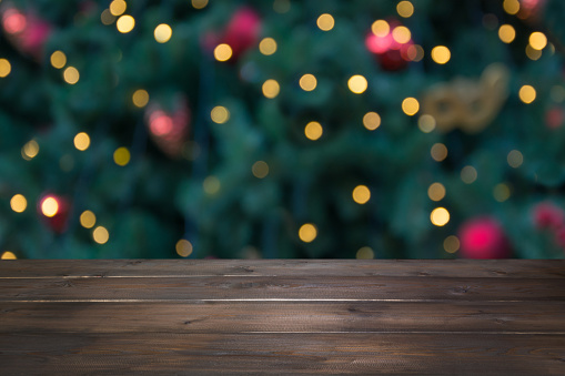 Wooden dark tabletop and blurred christmas tree bokeh. Xmas background for display or montage your products.