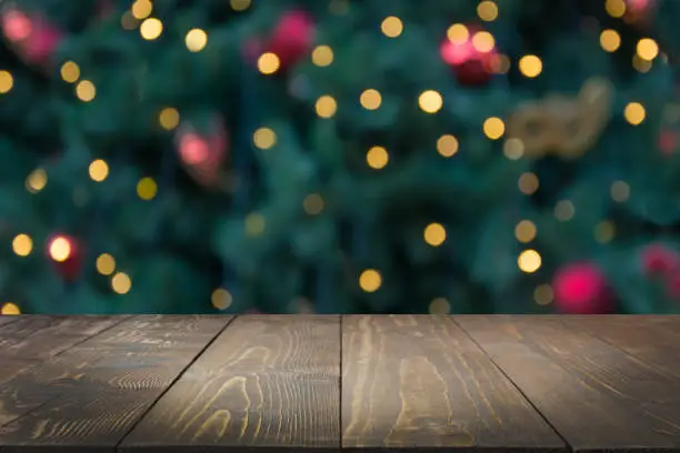 Photo of Wooden dark tabletop and blurred christmas tree bokeh. Xmas background for display your products.