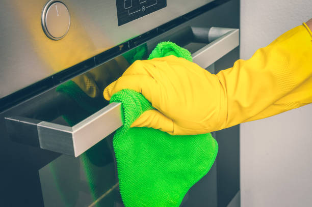 istock Hand in glove with green rag is wiping oven in kitchen 1044769554