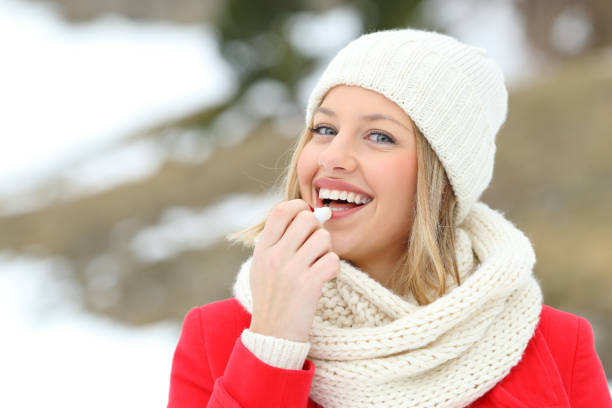 istock Happy woman applying lip balm outdoors in winter 1044770880