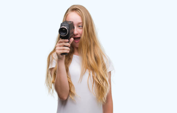 adolescent femme blonde tournage tenant une caméra super 8 peur en état de choc avec un visage de surprise, peur et excité par l’expression de la peur - super 8 video camera photos et images de collection