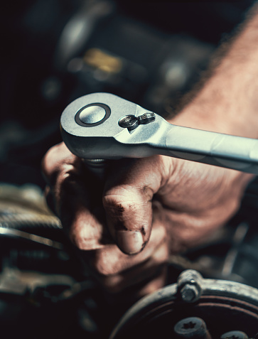 Auto mechanic working on car engine in mechanics garage. Repair service. authentic close-up shot