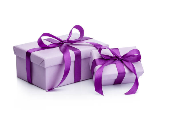Three-quarter front view of two gift boxes wrapped with purple craft paper shot on white background. The boxes are tied up with purple bows. Predominant colors are purple and white. Useful copy space available for text and/or logo. DSRL studio photo taken with Canon EOS 5D Mk II and Canon EF 70-200mm f/2.8L IS II USM Telephoto Zoom Lens