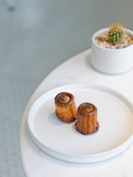 istock Assorted canneles on white round plate on white marble table with blur cactus plants 1044791502