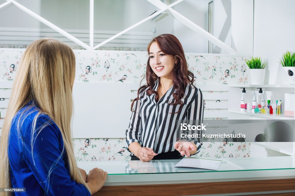 Beautiful young receptionist girl with a smile at the reception meets customers in the salon Hair Salon Stock Photo